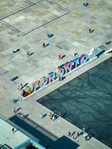 Sign reading "Toronto" with people walking around a central plaza